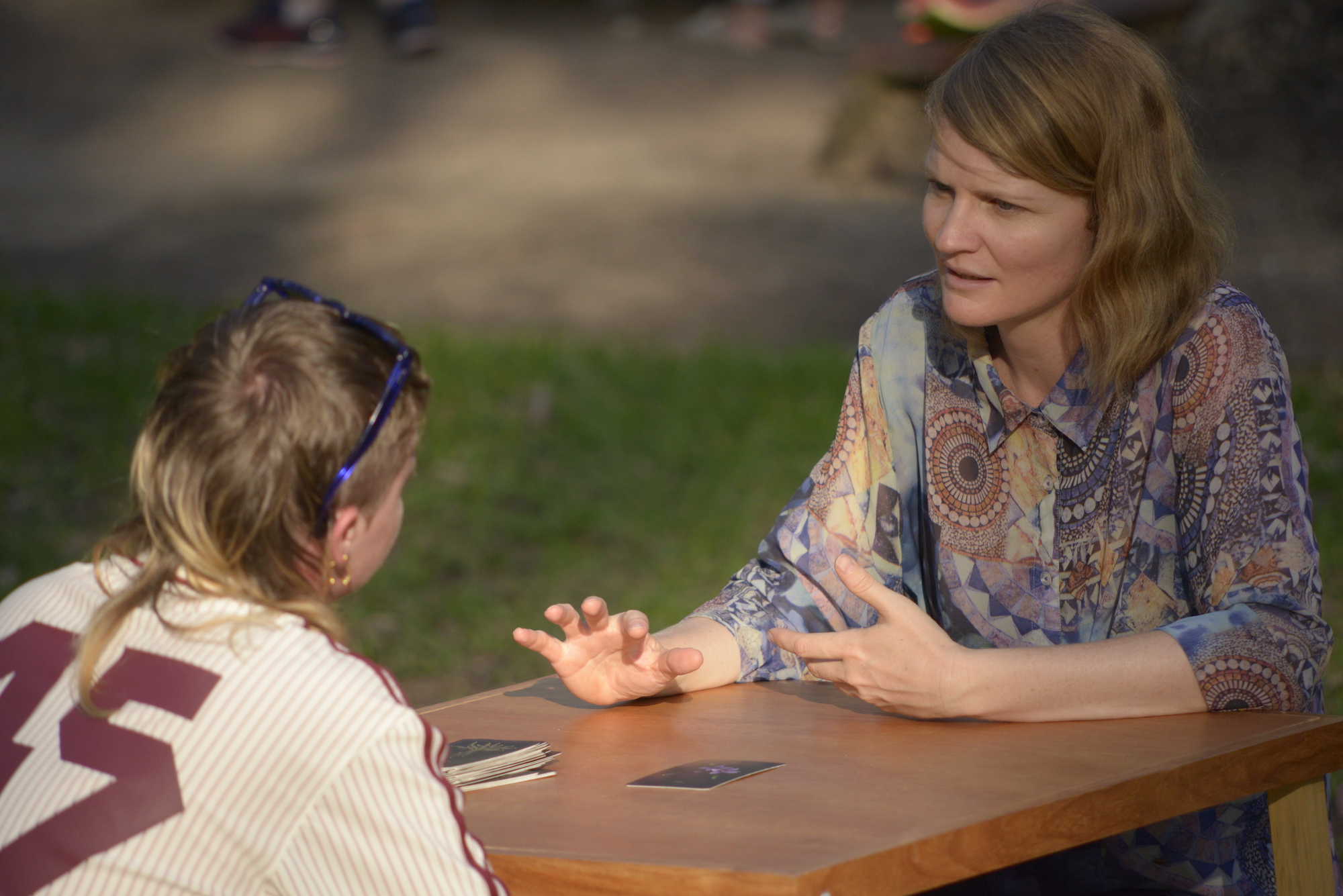 a woman reading divination cards for a person in a park